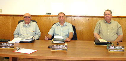 The PUD Board of Commissioners seated at a conference table and smiling.