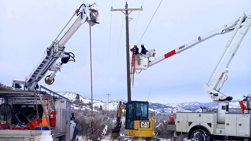 A crew of electric workers in cherry pickers and a Caterpillar  in winter