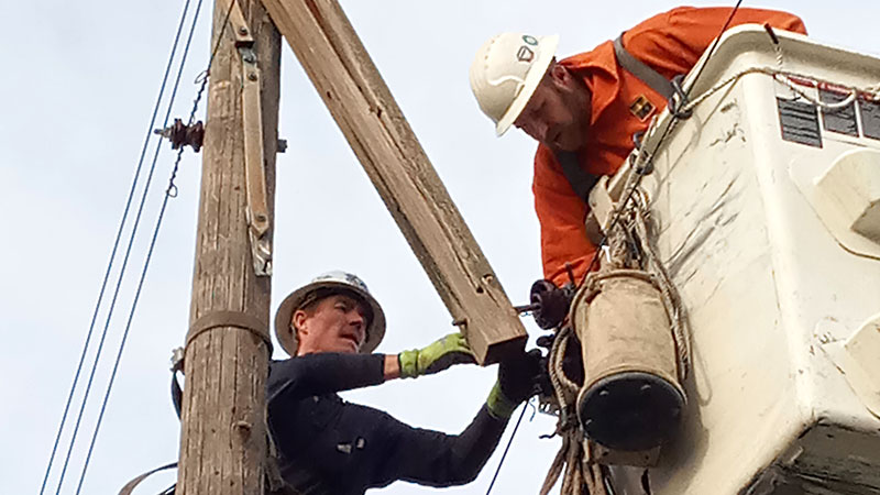 A closeup of two linemen working on a power line