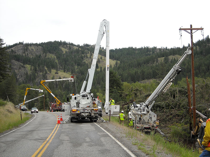 Several PUD equipment trucks on a highway to repair down power lines