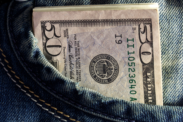 A pocket in a pair of jeans with a $50 bill sticking out, close up